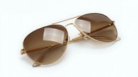 Stylish aviator sunglasses with gold metal frame and brown gradient lenses on white background, isolated fashion eyewear accessory for summer protection.