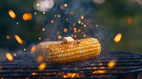 Grilled corn on barbecue with flying sparks and smoke in evening light, dramatic food photography with bokeh effect and dark moody atmosphere.