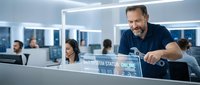 Middle-aged Caucasian businessman with beard smiling while reviewing data analytics on computer screen in modern corporate office environment.