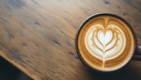 Cappuccino with heart latte art on wooden table, coffee shop atmosphere, barista crafted beverage for cafe menu and morning routine concepts.