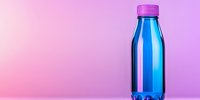 Blue plastic water bottle on pink and purple gradient background with copy space for text, minimalist style product photography for beverage marketing.