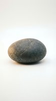 Single smooth gray river stone isolated on white background for zen meditation spa wellness and natural decoration concepts.