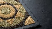 Assorted legumes and grains in wicker baskets on dark slate surface for healthy cooking and nutrition concepts.
