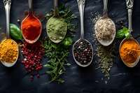 Colorful aromatic spices and herbs in vintage silver spoons on dark slate background, culinary ingredients for cooking.