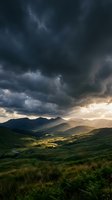 Dramatic storm clouds gather over rolling green mountains and valleys with golden sunlight breaking through, creating moody landscape scenery for nature and weather projects.