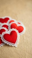 Red fabric hearts with white lace trim scattered on wooden surface for Valentine's Day romance and love themed crafts and decorations.