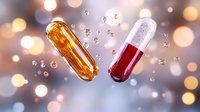Medical capsules with orange fish oil and red liquid medicine floating with sparkles and bubbles on blurred bokeh background for pharmaceutical concept.
