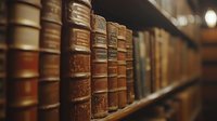 Vintage leather-bound books with gold lettering arranged on wooden shelf in library, creating atmospheric mood with shallow depth of field and warm lighting.