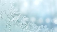 Delicate frost patterns on glass window with soft blue bokeh lights creating dreamy winter atmosphere for seasonal designs and holiday backgrounds.