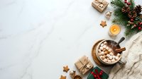 Overhead view of hot chocolate with marshmallows, wrapped gifts, evergreen branches, pinecones, cinnamon sticks, star cookies, and candle on marble surface for holiday celebrations.