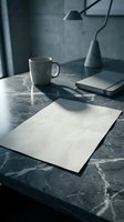 Minimalist workspace with blank paper sheet on marble desk, coffee mug and notebooks in moody lighting for creative projects and business planning.
