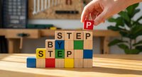 Hand placing wooden blocks spelling STEP BY STEP on desk in modern office workspace for business planning and goal achievement concepts.