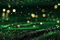 Magical emerald green bokeh background with golden glowing particles and sparkles floating in dark space creating dreamy festive atmosphere.