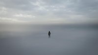 Solitary figure standing in vast misty landscape with overcast sky, conveying isolation, contemplation, and minimalist atmosphere for editorial and conceptual projects.