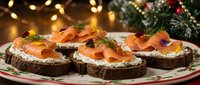 Festive smoked salmon appetizers on dark bread with cream cheese and herbs, perfect for holiday entertaining and Christmas party catering menus.