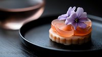 Elegant caramel dessert tart with purple flower garnish on dark plate, gourmet pastry presentation for fine dining and culinary photography.