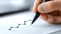 Hand drawing upward trending arrow graph with black pen on white paper showing business growth and success metrics for financial planning presentations.