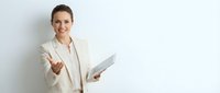 Professional businesswoman in beige suit holding documents and extending hand for handshake against white background for corporate presentations.