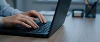 Professional businessman hands typing on laptop keyboard at modern office desk workspace for productivity and business communication.