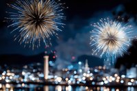 Spectacular fireworks display bursting over city skyline at night with golden sparks and colorful explosions illuminating urban landscape for celebration events.