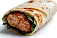 Grilled chicken wrap with fresh spinach leaves and sauce rolled in flour tortilla on white background, close up view of appetizing lunch sandwich.