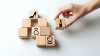 Hand placing wooden cube with padlock icon among blocks featuring high heel, wedding ring and person symbols on white background for security concept.