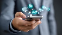 Glowing message icons floating above smartphone in businessman's hands, depicting digital communication and mobile messaging technology in modern business setting.