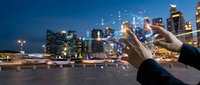 Businessman hands holding smartphone with digital network connections over modern city skyline at night, representing technology and urban connectivity.