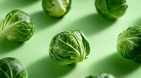 Fresh Brussels sprouts scattered on green background for healthy cooking and nutrition concepts.
