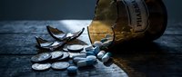 Prescription medication pills spilling from amber bottle on dark wooden surface. Healthcare, pharmacy, medical treatment and drug safety concept.
