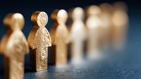 Golden wooden figures standing in line on dark textured surface, representing leadership, teamwork, and organizational hierarchy in business concept.