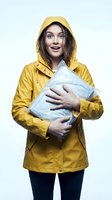 Young woman with long dark hair and fair complexion wearing bright yellow raincoat holding wrapped package, expressing excitement and joy. Suitable for delivery, shipping, online shopping and logistics marketing materials.