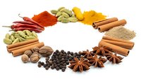 Colorful spices and herbs arranged in circular pattern on white background. Cinnamon sticks, star anise, cardamom, turmeric, paprika for cooking.