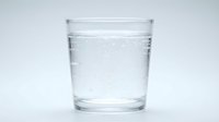 Clear glass of sparkling water with bubbles on white background isolated for health and hydration concepts.