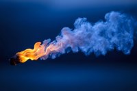 Burning match with orange flame and blue smoke trail against dark background, dramatic lighting creates mystical atmosphere for creative concepts.
