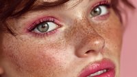 Close-up portrait of young Caucasian woman with natural freckles and pink makeup. Fresh skincare and beauty concept for cosmetics advertising.