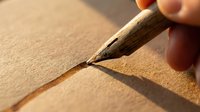 Close-up of a woodburning tool creating detailed lines on light wood surface, demonstrating pyrography technique for crafts and artistic design projects.