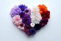 Colorful dahlia flowers arranged in heart shape with white candle on light background, romantic floral composition for wedding, valentines day and celebrations.