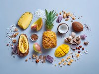 Tropical fruits and spices arranged on blue background, including pineapple, mango, coconut, and exotic ingredients for culinary use.