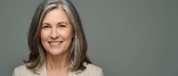Mature woman with long gray hair and fair complexion smiling at camera against neutral background, suitable for healthcare, wellness, corporate, and lifestyle marketing materials.