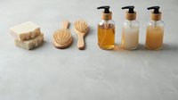 Natural organic skincare products with soap bars, wooden brushes and pump bottles containing oils and lotions arranged on neutral background for spa wellness.