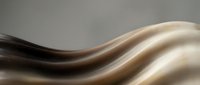 Smooth flowing waves of dark brown and cream colored silk fabric creating an elegant abstract composition with soft lighting and depth.