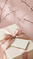 Elegant gift box with pink satin ribbon and blank card against soft pink background with delicate cherry blossom branches for special occasions.