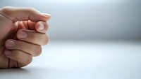 Clasped hands in prayer position on white surface showing faith, meditation, spirituality and peaceful contemplation for wellness and mindfulness concepts.