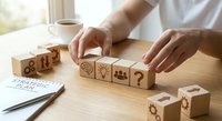 Business strategy planning with wooden blocks featuring icons for goal setting and decision making process on office desk.