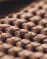 Extreme close-up macro shot of milk chocolate bar texture showing detailed pattern of squares with soft focus and warm brown tones, suitable for food industry use.