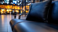 Black leather armchair with decorative pillow in modern office lobby or business center interior with blurred city lights background at night.