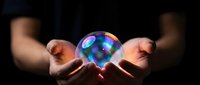 Hands holding glowing crystal ball with colorful light reflections against dark background for fortune telling and mystical predictions concept.