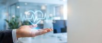 Healthcare technology concept with businessman hand presenting digital heart pulse monitor in modern medical office environment for telemedicine applications.