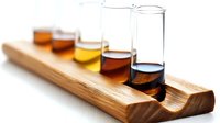 Laboratory test tubes with colorful liquid samples arranged in wooden holder on white surface, scientific research concept for chemistry experiments.
